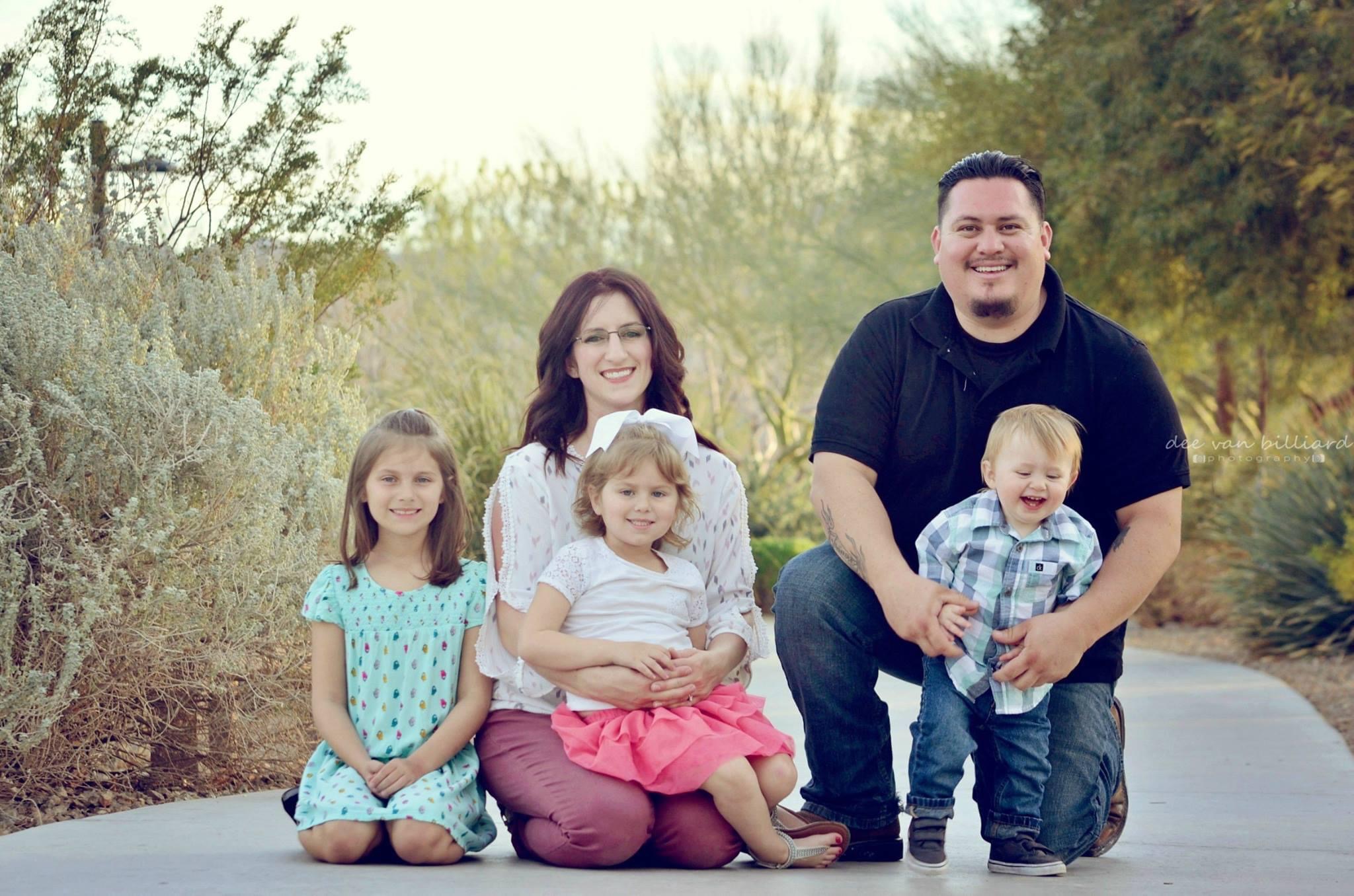 A family of five smiling at the park.