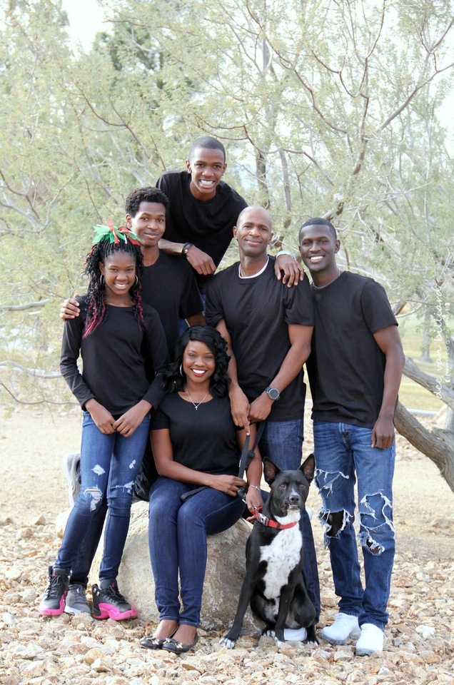 A family of six pose outside with their dog.