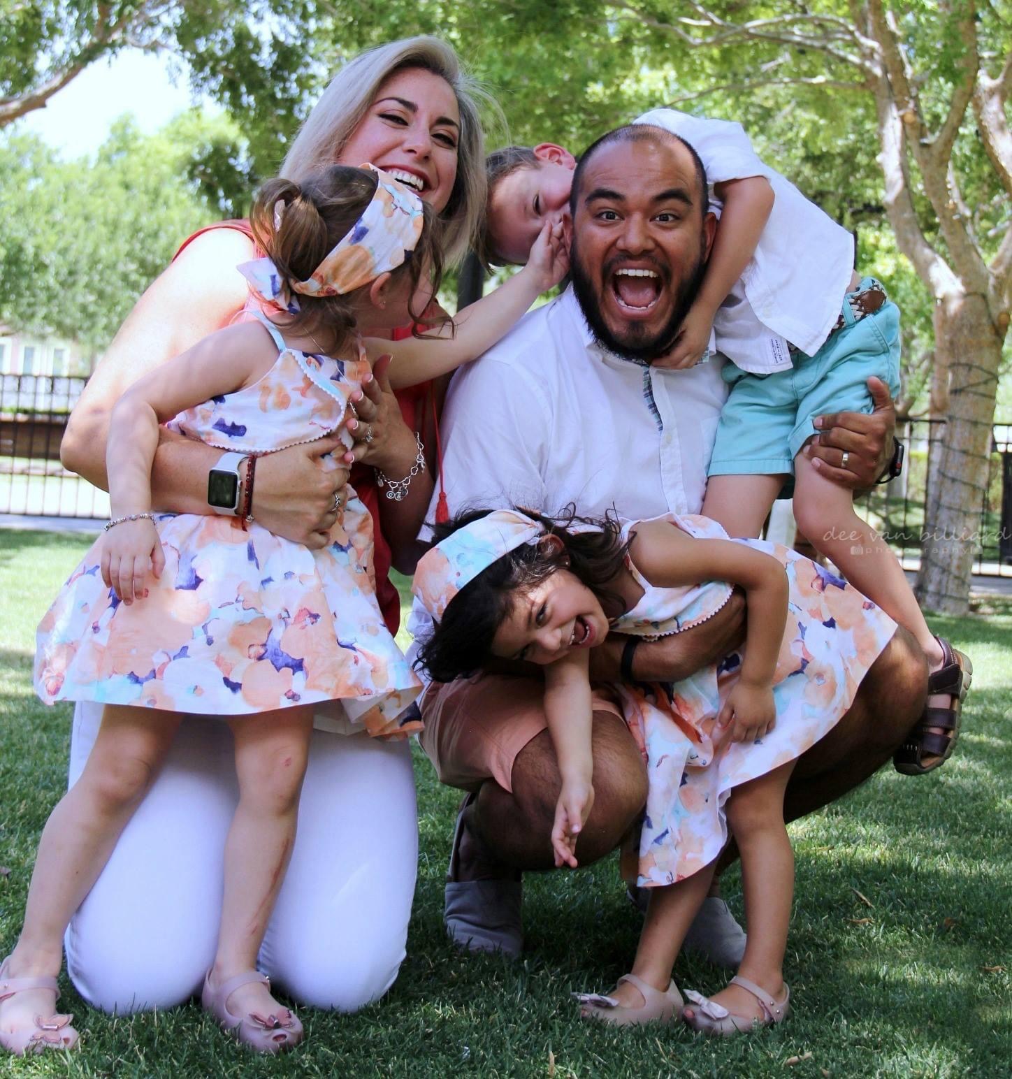 A couple and their three kids laughing during a photo.