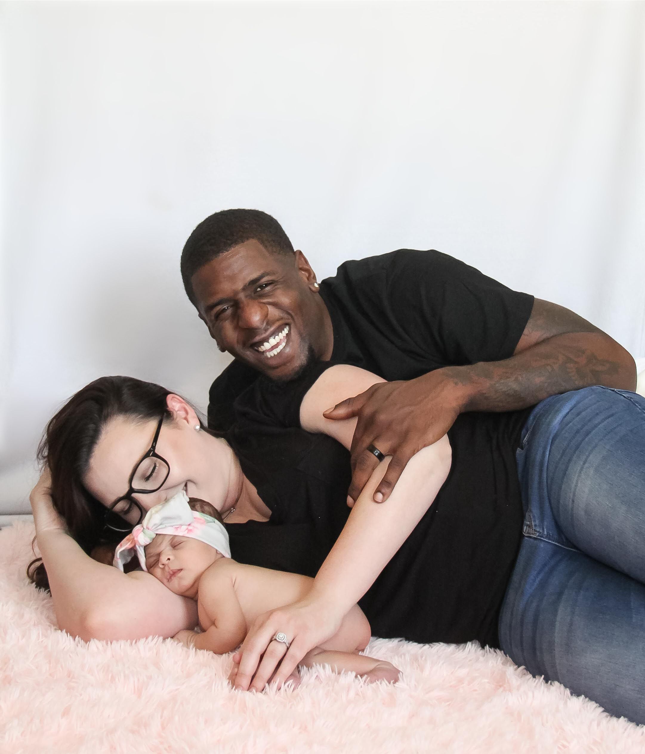 A father, mother, and baby smiling for a photo.