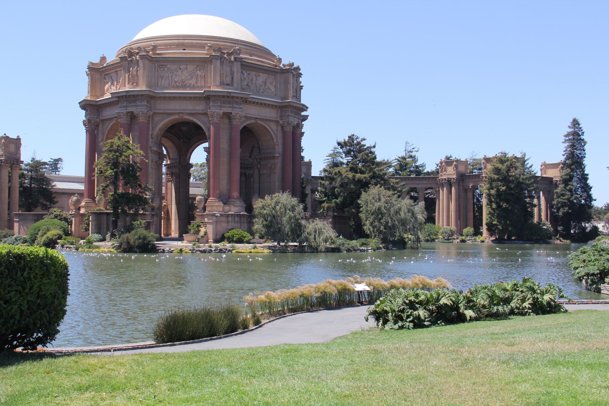 The palace of fine arts displays its old-fashioned architecture beside a small body of water.