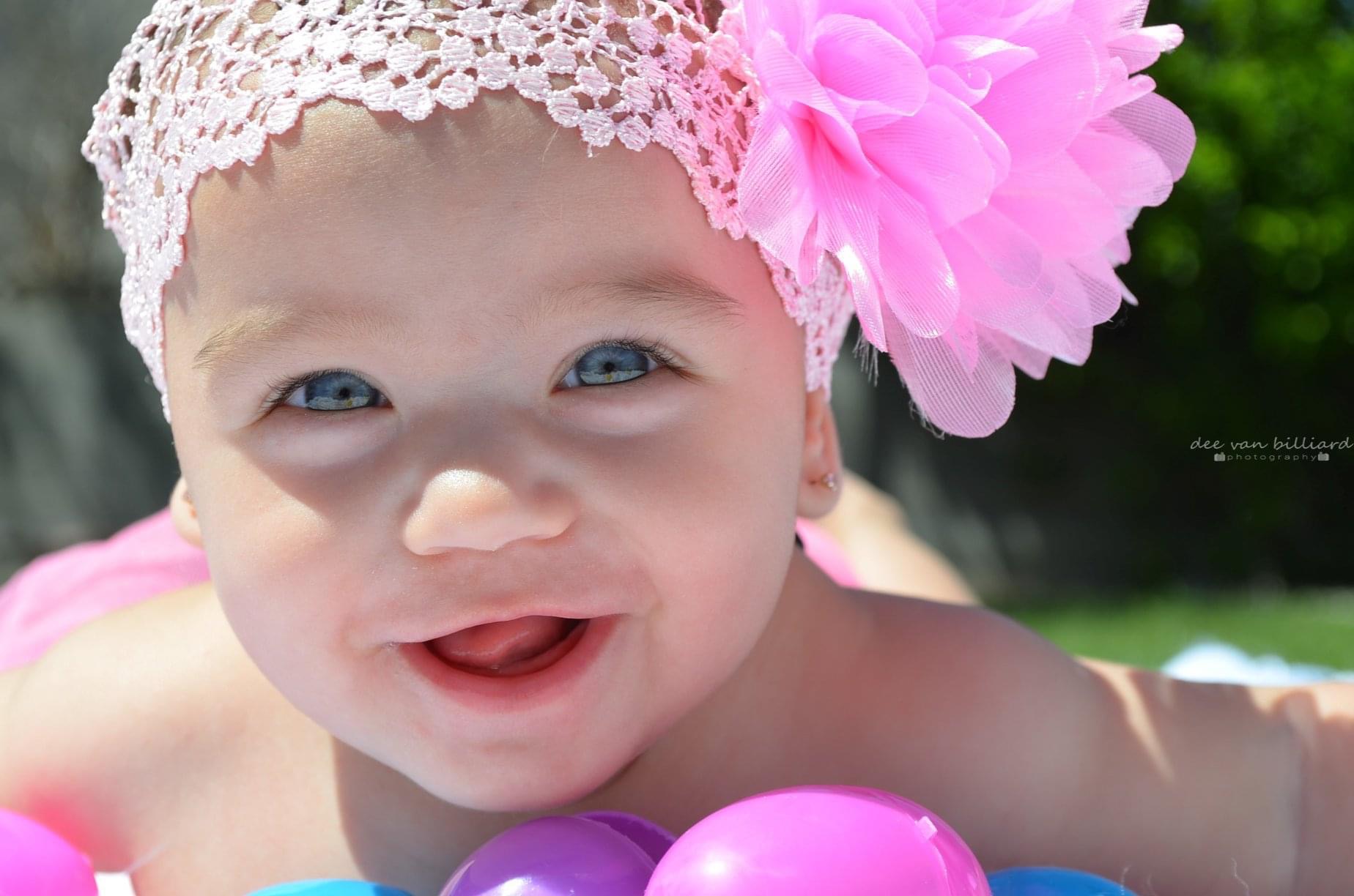 A blue-eyed baby smiling for a photo.